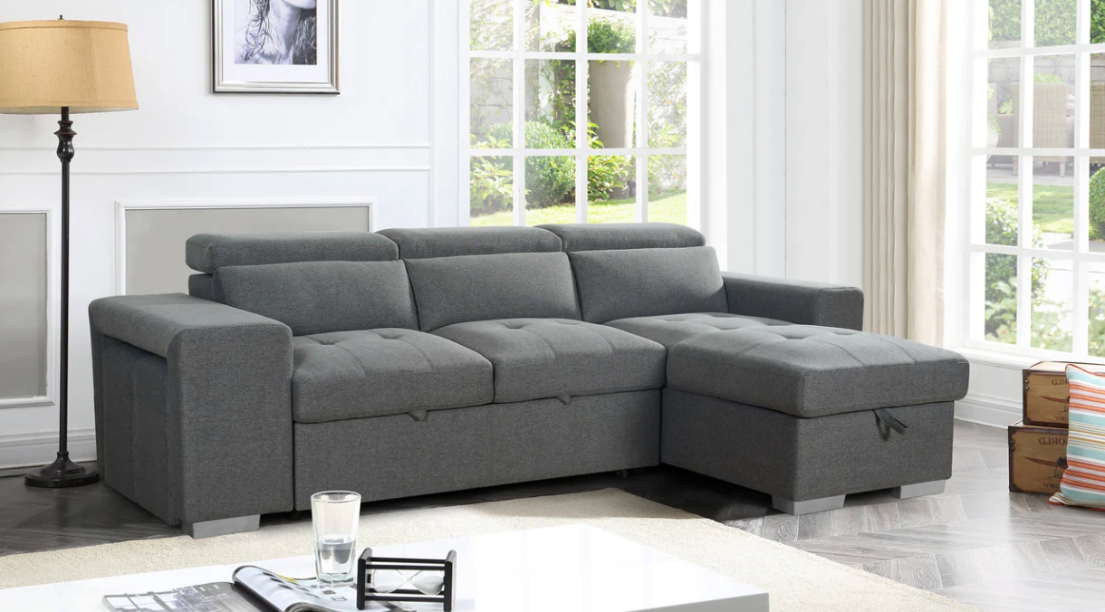 Gray sectional sofa in a living room with a lamp and coffee table.