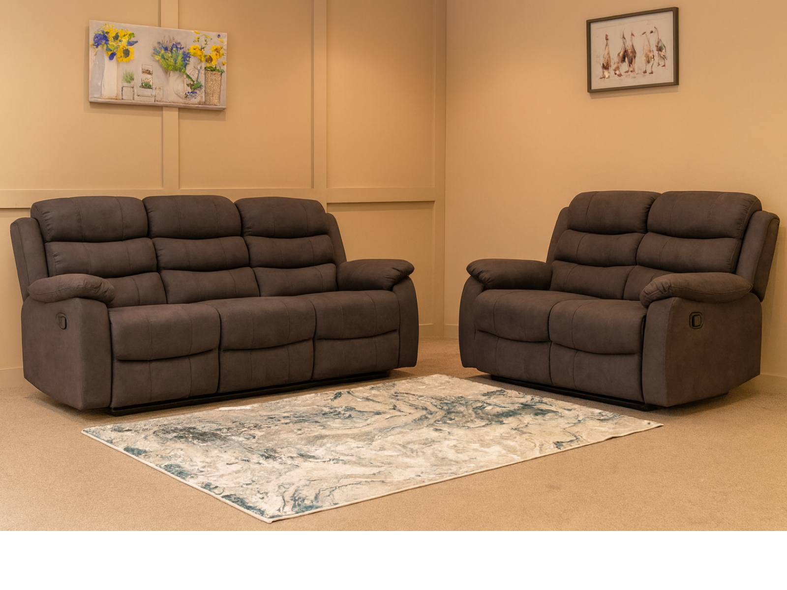 Brown reclining sofa set in a room with a floral rug and framed pictures on the wall.