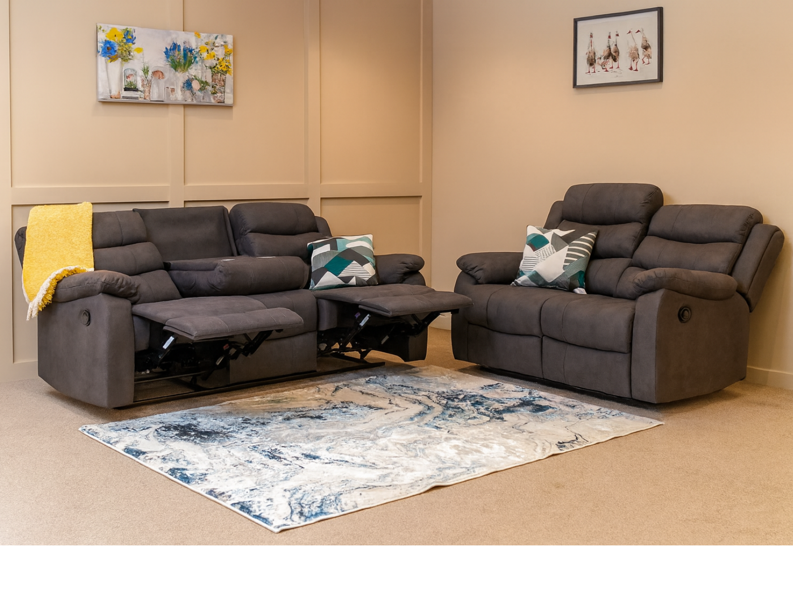 Gray recliner sofa set in a living room with a decorative rug and wall art.